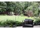 View of a backyard with a green lawn, mature trees, and outdoor seating at 405 Mallory Cir, Loganville, GA 30052