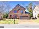 Charming two-story stone home with red shutters, arched entryway, and manicured front lawn at 4595 Carriage Walk Ln, Cumming, GA 30040