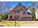 Charming two-story stone home with red shutters, arched entryway, and manicured front lawn at 4595 Carriage Walk Ln, Cumming, GA 30040