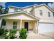 Two-story home featuring a covered porch, two-car garage, and manicured shrubs at 411 Hopi Ln, Villa Rica, GA 30180