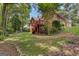 Brick home with a stained wood deck, a covered patio, and a lush green lawn, surrounded by mature trees at 821 Carnellian Ln, Peachtree City, GA 30269