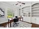 Well-lit home office with built-in shelving, a wooden desk, and patterned rug at 1220 Roswell Manor Cir, Roswell, GA 30076