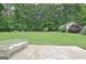 Large grassy backyard with patio, bench, storage building and lush trees offering an oasis of privacy at 210 Grandchester Way, Fayetteville, GA 30215