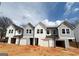 New townhomes with neutral siding, garages and covered entries beneath black rooflines at 11594 E Lovejoy Rd # 1, Hampton, GA 30228
