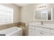 Bathroom featuring a tub, a white vanity, and a bright, neutral-toned interior at 1421 Oak Knoll Ne Dr, Conyers, GA 30012
