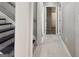 Hallway with white walls and tile floors leading to various rooms with black stairs on the left side at 3368 Alhambra Cir, Hampton, GA 30228