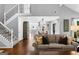 Bright living room featuring a staircase, hardwood floors, and an open view to the kitchen and dining area at 431 Hampton Grn, Peachtree City, GA 30269