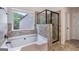 Bathroom featuring a soaking tub, glass shower, and gray tile surround at 2307 Loughridge Dr, Buford, GA 30519