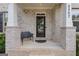 Inviting front porch of a brick home with a covered entrance and a black metal bench at 2307 Loughridge Dr, Buford, GA 30519