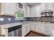 A close view of the kitchen showcasing white cabinets, stainless appliances, granite counters, and a stylish subway tile backsplash at 2307 Loughridge Dr, Buford, GA 30519