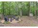 Backyard retreat with a gravel firepit and chairs surrounded by lush greenery and a wooden fence at 15 Stonewood Way, Sharpsburg, GA 30277