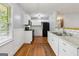 Bright kitchen features white cabinets, black appliances, hardwood floors and a view of the eat-in kitchen nook at 4653 Ridgewood Dr, Forest Park, GA 30297