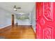 Open living room with hardwood floors, ceiling fan, and a view into the kitchen, entering through the red front door at 4653 Ridgewood Dr, Forest Park, GA 30297