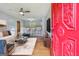 Staged living room boasts hardwood floors, ceiling fan, and a view of the kitchen; entering through the red front door at 4653 Ridgewood Dr, Forest Park, GA 30297