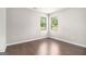 A bedroom featuring hardwood floors, natural light from two windows, and neutral wall paint at 8041 Louis Dr, Locust Grove, GA 30248