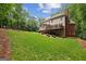 Large backyard featuring lush lawn, mature trees, and brick home with wooden deck at 770 Spalding Heights Dr, Atlanta, GA 30350