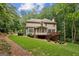 Expansive home backyard featuring lush lawn, mature trees, covered porch, and wooden deck at 770 Spalding Heights Dr, Atlanta, GA 30350