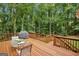 Wooden deck featuring outdoor dining furniture, grill and wood railing overlooking lush trees at 770 Spalding Heights Dr, Atlanta, GA 30350
