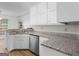 Well-lit kitchen featuring white cabinets, granite countertops, and stainless steel dishwasher at 404 Northwind Pl, Stockbridge, GA 30281