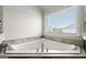 Corner bathtub with neutral tile surround next to a large bright window at 4105 Vista Pointe Dr, Cumming, GA 30028