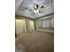 A carpeted bedroom with a ceiling fan, a tray ceiling, two large closets, and a window seat at 207 Oak N Cir, Stockbridge, GA 30281