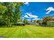 Expansive backyard with lush green lawn, mature trees, metal building, and covered parking area at 3700 Tom Brewer Rd, Loganville, GA 30052