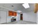 Unfinished basement featuring concrete floor, shelving, utility door, and a paint-ready white wall at 3700 Tom Brewer Rd, Loganville, GA 30052