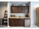 Wet bar area featuring brown cabinets, stainless steel mini-fridge, and granite countertops, perfect for entertaining at 293 Ironwood Dr, Stockbridge, GA 30281