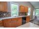 Well-lit kitchen with oak cabinets, tiled backsplash, and stainless steel double sink and black dishwasher at 616 Inman Rd # B, Fayetteville, GA 30215