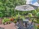 Outdoor patio with a striped umbrella, a glass-top table, and chairs, surrounded by lush plants and flowers at 4147 Alayna Lee Cir, Mcdonough, GA 30252