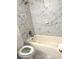 Bathroom features marble-like tiled walls, shower-tub combo and white toilet at 7813 Sugarland Dr, Jonesboro, GA 30236