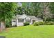 Well-kept white home with lush green lawn, mature trees, and a charming design at 345 Sharon Dr, Fayetteville, GA 30214