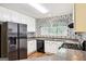 Well-lit kitchen featuring white cabinets, black appliances, stylish patterned wallpaper, and wood floors at 345 Sharon Dr, Fayetteville, GA 30214