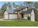Charming home featuring stone accents, a two-car garage, a lush lawn, and mature trees in a serene setting at 5368 Nw Stafford Nw Dr, Lilburn, GA 30047