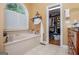 Bright bathroom with a soaking tub and a window with shutters, alongside an open closet at 204 Pinehurst Way, Carrollton, GA 30116