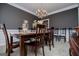 Formal dining room features a stylish chandelier and dark wood furniture for elegant gatherings at 204 Pinehurst Way, Carrollton, GA 30116