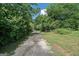 Gated gravel driveway leading to a private residence through lush greenery and mature trees in a serene setting at 500 Happy Hollow Rd, Villa Rica, GA 30180
