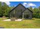 Modern black home with large windows and patio seating area with views of a well manicured lawn at 500 Happy Hollow Rd, Villa Rica, GA 30180