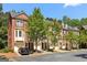 Attractive brick townhomes with attached garages and manicured trees lining a quiet street at 56 American Walk, Peachtree City, GA 30269