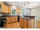 Well-lit kitchen with wood cabinets, black appliances, hardwood floors, and a kitchen island at 56 American Walk, Peachtree City, GA 30269