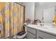 Bathroom featuring a yellow-themed shower curtain, single vanity, and neutral-toned floor tiles at 3711 Wartrace Dr, South Fulton, GA 30331