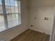 A small laundry room with wood-look floors, washer/dryer hookups, and a window with blinds at 1238 Polk Xing, Mcdonough, GA 30252