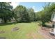 Lush backyard with mature trees, fire pit, and distant view of the house, perfect for outdoor gatherings at 634 Skyline Dr, Villa Rica, GA 30180