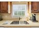 Close-up of a stainless steel sink with a window view, wood cabinets, and countertop appliances at 595 Mcgarity Dr, Mcdonough, GA 30252