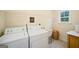 Bright laundry room with washer, dryer, utility sink, wire shelves and window with view at 595 Mcgarity Dr, Mcdonough, GA 30252