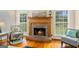 Cozy living room featuring a brick fireplace, wood mantle, and lots of natural light from the surrounding windows at 595 Mcgarity Dr, Mcdonough, GA 30252