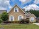 Two-story stucco home with white trim plus landscaped front yard with blooming azalea bushes and a retaining wall at 141 Wexford Ct, Stockbridge, GA 30281