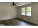 Spacious bedroom featuring two windows, a ceiling fan, crisp white walls, and dark wood-look flooring at 276 Oakland Rd, Mcdonough, GA 30253