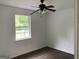 Bright bedroom showcasing a window, a ceiling fan, white walls, and modern wood-look flooring at 276 Oakland Rd, Mcdonough, GA 30253