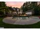 Stunning backyard pool with stone accents and an expansive patio, perfect for outdoor entertaining at dusk at 307 Bellingrath Ct, Peachtree City, GA 30269